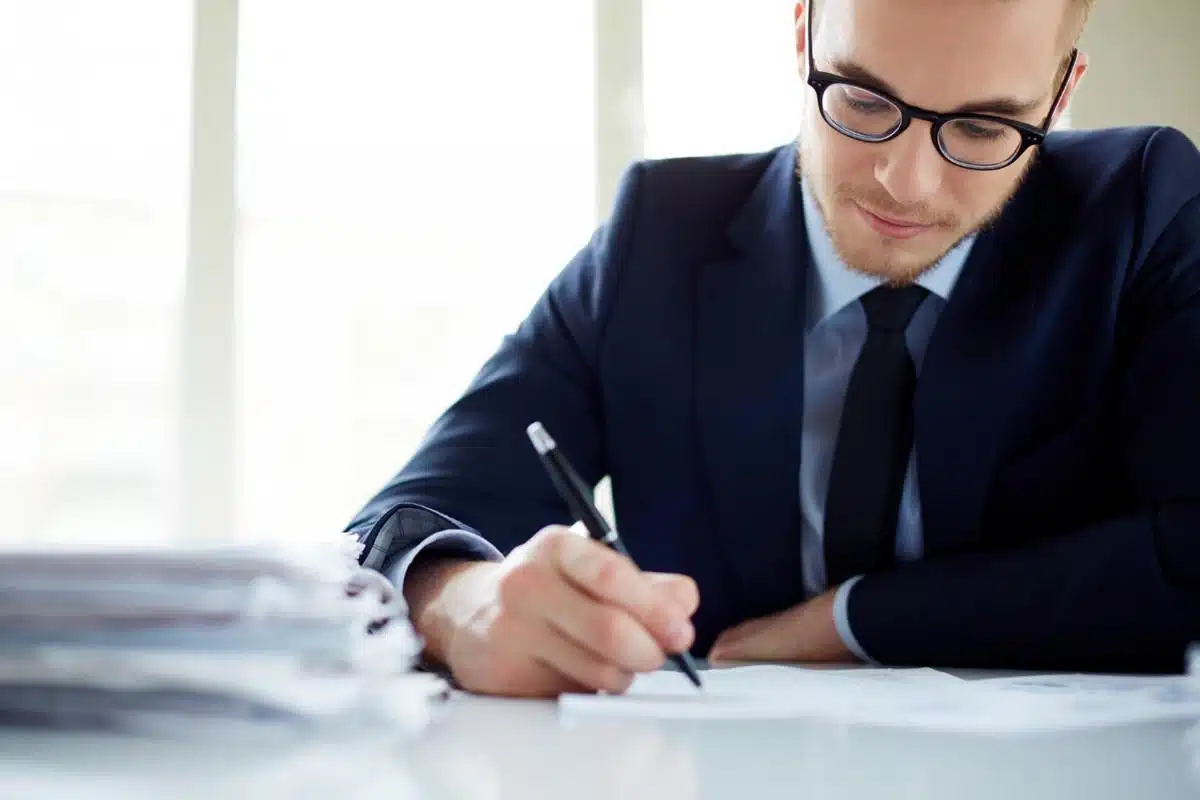 Professional lawyer in a suit reviewing legal documents at a desk with stacks of paperwork