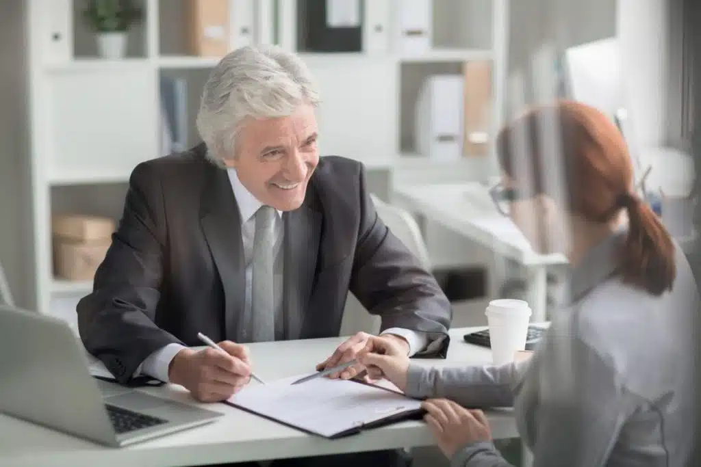 Experienced attorney smiling while consulting client on a tax evasion case in a modern office.