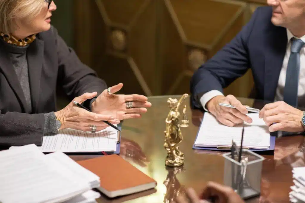 Tax lawyer and client in a legal office discussing wage garnishment solutions, with legal documents and a golden Lady Justice statue on the table.