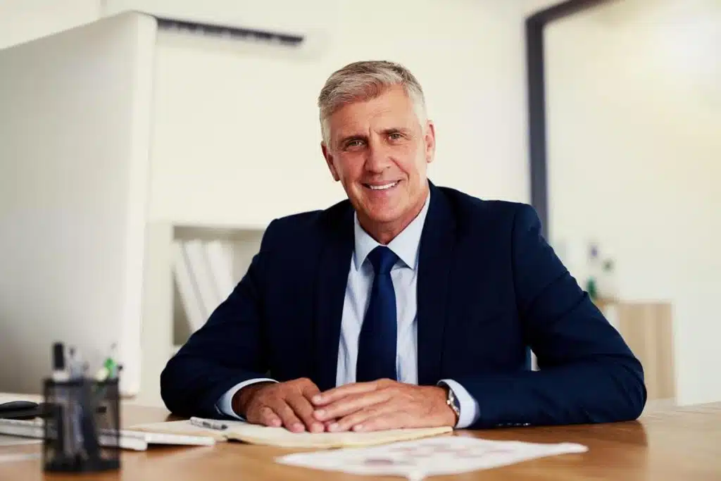 Smiling professional tax lawyer in Miami sitting at his office desk with documents.